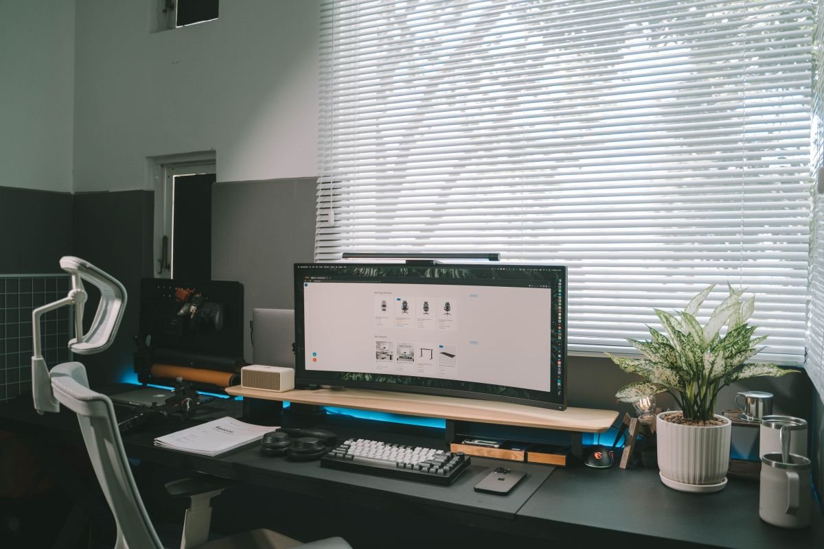 An affordable small desk with a monitor and plants by a window