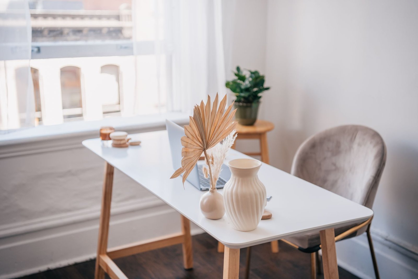 A bright, aesthetic small home office with a white desk and morning light