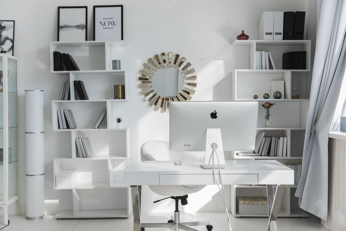 A white wall-mounted shelving desk unit in a bright room